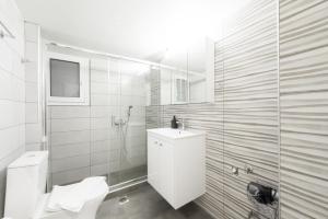 a white bathroom with a toilet and a sink at New Spacious & Stylist Apt in Piraeus