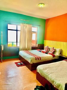 Duas camas num quarto com paredes verdes e laranja em Mountain Resort em Nagarkot