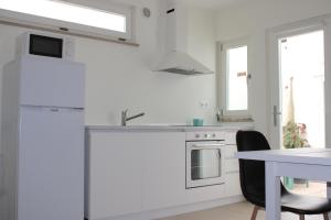 a white kitchen with a sink and a table at Estudio Hortas in Vila do Bispo
