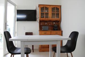 a dining room with a white table and two black chairs at Estudio Hortas in Vila do Bispo