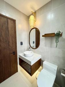 uma casa de banho com um WC, um lavatório e um espelho. em Tropicana Hồ Tràm - Seashell Villa em Ho Tram