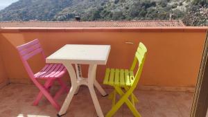 un tavolo e sedie su un balcone con vista di Isola del Giglio casa Nico e casa Camilla Monticello Giglio Porto a Giglio Castello