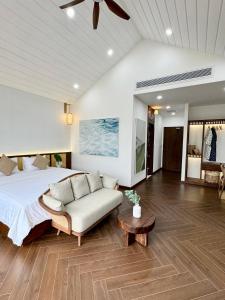 a bedroom with a bed and a couch and a table at Tropicana Hồ Tràm - Seashell Villa in Ho Tram