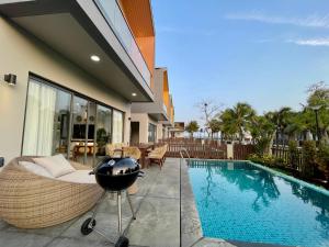 a swimming pool with a grill next to a house at Tropicana Hồ Tràm - Seashell Villa in Ho Tram