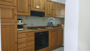 a kitchen with wooden cabinets and a black dishwasher at Isola del Giglio casa Nico e casa Camilla Monticello Giglio Porto in Isola del Giglio