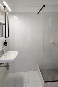 a white bathroom with a sink and a shower at VIRI VIRI APARTMENTS in Lilikás