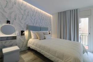 a bedroom with a white bed and a mirror at Suite apartment mar menuda in Tossa de Mar