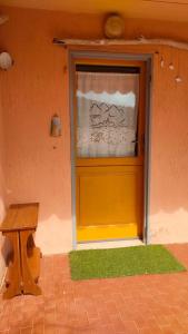 une porte jaune avec une fenêtre et un banc dans l'établissement Isola del Giglio Casa Cecilia GIGLIO Porto loc Monticello, à Isola del Giglio