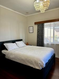 Un dormitorio con una cama grande y una lámpara de araña. en Charming Brick Homestay Room in Northam en Northam