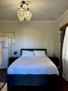1 dormitorio con 1 cama blanca y 2 lámparas de araña en Charming Brick Homestay Room in Northam en Northam