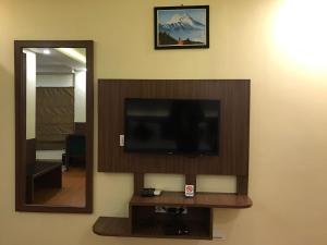 a flat screen tv on a wall next to a mirror at Nepalirika Hotel Damak in Pānigata