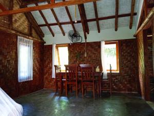 a dining room with a table and chairs and windows at Magpie homestay in Bukit Lawang