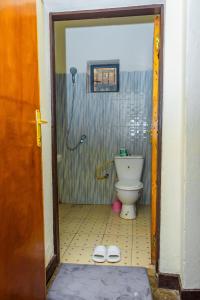 La salle de bains est pourvue de toilettes et d'une paire de chaussons. dans l'établissement Rhoja homes, à Ruhengeri