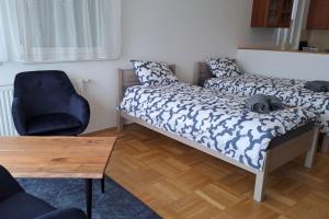 a room with two beds and a desk and a chair at Charm Apartment in Kecskemét