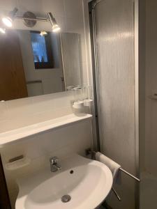 a white bathroom with a sink and a mirror at Wappensaal Dhaun in Hochstetten-Dhaun
