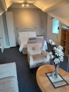 um quarto com uma cama e uma mesa com um vaso de flores em Singleton Short Stay Loft R10 em Swansea