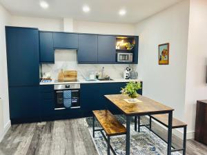 uma cozinha com armários azuis e uma mesa de madeira em Central Buxton apt in Spring Gardens em Buxton