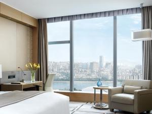 a bedroom with a bed and a desk and a large window at Langham Place Guangzhou - Walking distance to Canton Fair in Guangzhou