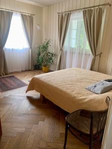 ein Schlafzimmer mit einem Bett, einem Stuhl und einem Fenster in der Unterkunft Pušyno apartamentai in Druskininkai