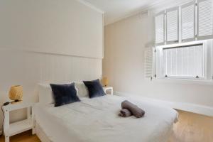 a bedroom with a white bed with blue pillows and a window at 2 Bedroom House with 2 E-Bikes Included at Centre of Chippendale in Sydney
