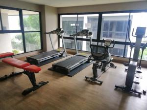 a gym with treadmills and machines in a room with windows at Sukhumvit​ 101 in Phra Khanong