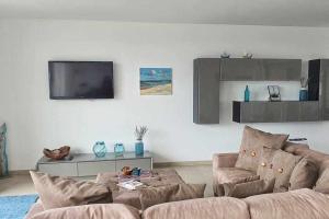 uma sala de estar com um sofá e uma televisão em Fantástica V3 Vista Mar Golfe Praia Del Rey em Amoreira