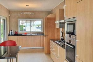 uma cozinha com armários de madeira e uma cadeira vermelha em Fantástica V3 Vista Mar Golfe Praia Del Rey em Amoreira