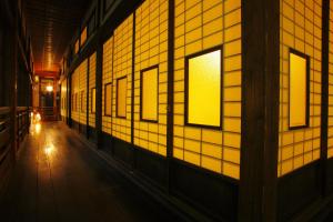 白石市にある時音の宿　湯主一條の黄色のタイルの壁と窓のある廊下