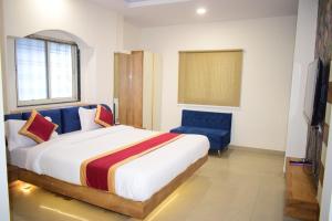 a bedroom with a large bed and a blue chair at Hotel Signor in Indore