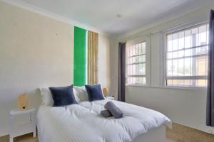 a bedroom with a white bed with a green wall at Affordable 3 Bedroom House Darlinghurst with 2 E-Bikes Included in Sydney
