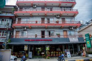 a tall building with a red balcony on a street at Rosemary Homes Pokhara in Pokhara