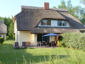 a house with a thatched roof with a table and chairs at Behagliches Reetdachhaus Eibe 1 in Puddemin