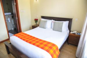 a bedroom with a large bed with a plaid blanket on it at Fedha Residences by Trianum in Nairobi