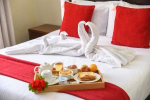 a tray of food on a bed with swan shaped towels at Fedha Residences by Trianum in Nairobi