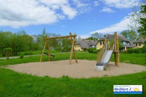 a playground with a slide in the sand at Familienfreundliches Reetdachhaus Weissdorn 2 in Puddemin