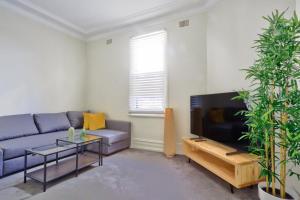 a living room with a blue couch and a tv at Unique 2 Bedroom Darling Harbour Glebe 2 E-Bikes Included in Sydney