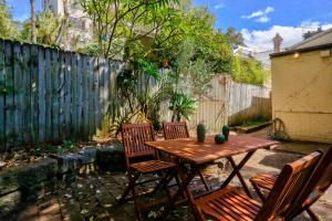 een patio met een houten tafel en stoelen en een hek bij Unique 2 Bedroom Darling Harbour Glebe 2 E-Bikes Included in Sydney