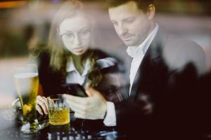 Hola Hotel Katowice في كاتوفيسي: رجل وامرأة يجلسون على طاولة مع المشروبات