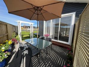 un patio con una mesa de cristal y una sombrilla en Studio on Patete en Taupo