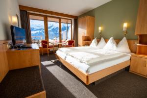 ein Hotelzimmer mit einem großen Bett und einem TV in der Unterkunft Hotel Jungfraublick in Wengen