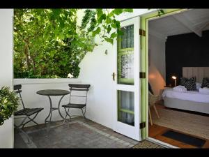 una puerta que conduce a un patio con una mesa y una cama en Ashbourne Boutique Guest House, en Franschhoek