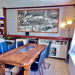 Chalet la Pagode, vue Mont-Blanc et jardin privé في شامونيه مون بلان: طاولة خشبية كبيرة في مطبخ مع كراسي زرقاء