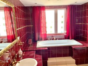 W łazience znajdują się czerwone zasłony, wanna i umywalka. w obiekcie Apartament relax 4 w mieście Międzyzdroje