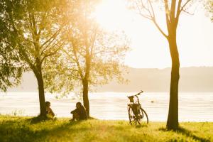 dos personas sentadas en el césped cerca del agua con una bicicleta en Insel der Sinne, en Görlitz