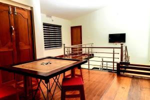 Cette chambre dispose d'une table, de chaises et d'un balcon. dans l'établissement pookode villa, à Vythiri