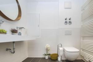 a white bathroom with a toilet and a mirror at 2: Schöne Schwabing 70m² sannierte City Wohnung in Munich