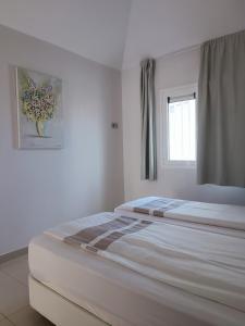 een witte slaapkamer met een bed met een vaas aan de muur bij SEA VIEW APARTMENTS in Costa Calma