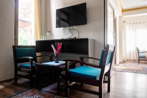 ein Wohnzimmer mit einem Tisch, Stühlen und einem TV in der Unterkunft Hotel Wangchen in Leh