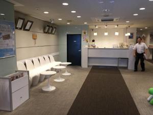 a man standing in a waiting room with tables and chairs at Hotel Green Palace in Sendai