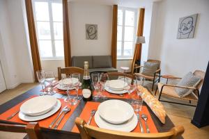 a dining room with a table with plates and wine glasses at Au 38, Charme et Confort dans notre T2 à Epernay in Épernay